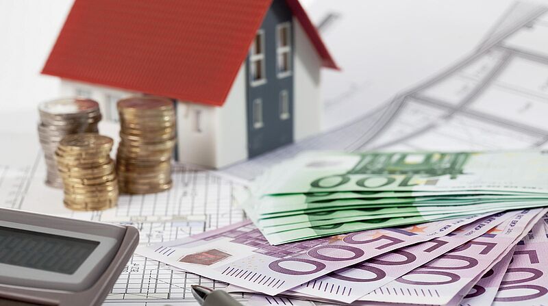 Förderung Hausbau Hauskauf, Geldscheine liegen vor Modellhaus