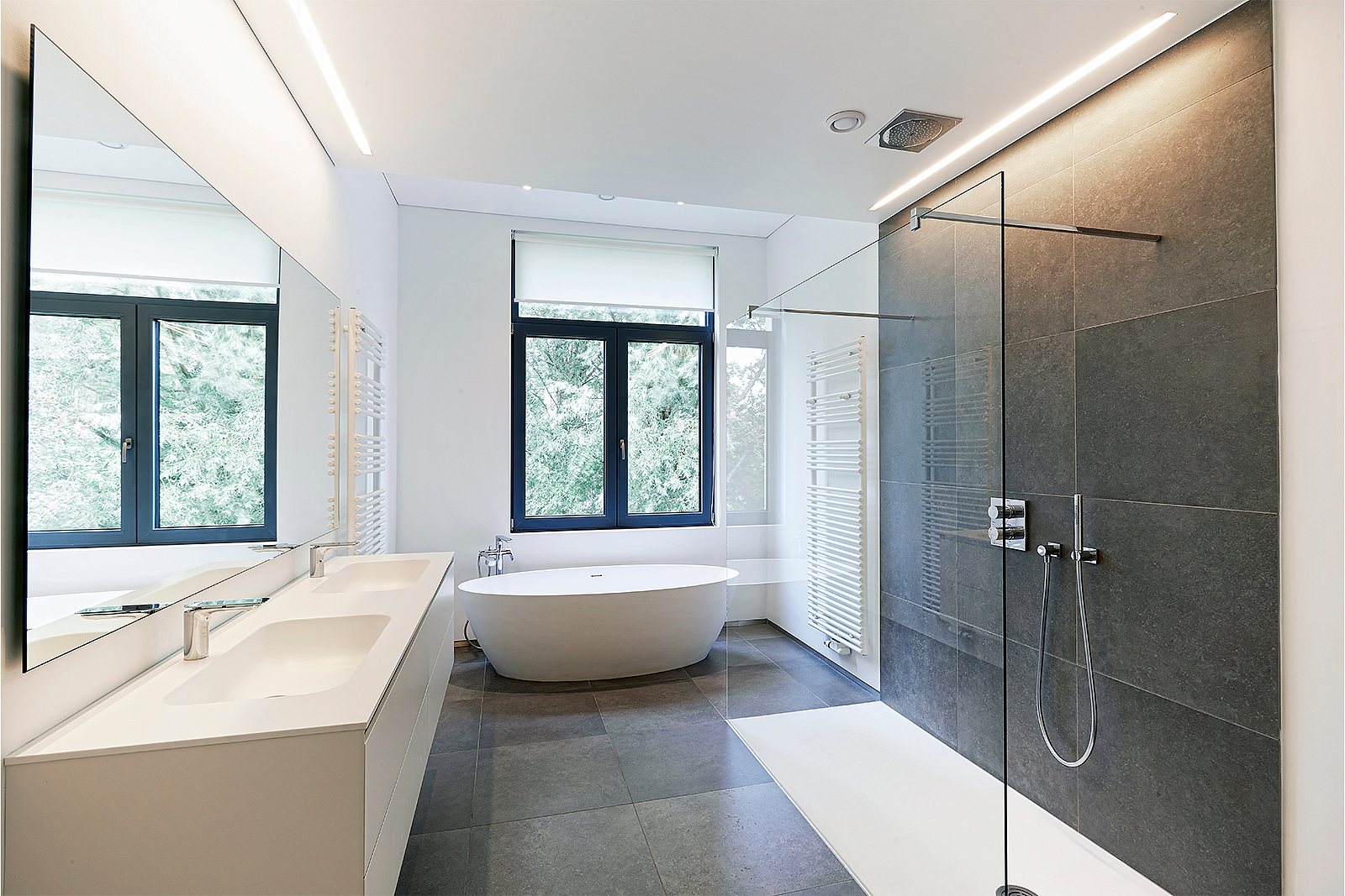 Ein saniertes Bad mit neuer bodengleicher Dusche, Waschtisch und einer Badewanne. 