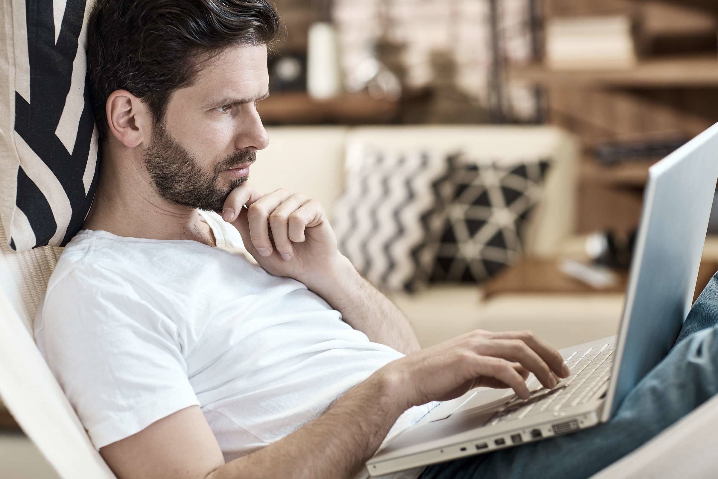 Mann recherchiert am Laptop zu einer Baufinanzierung für Singles und Alleinverdiener