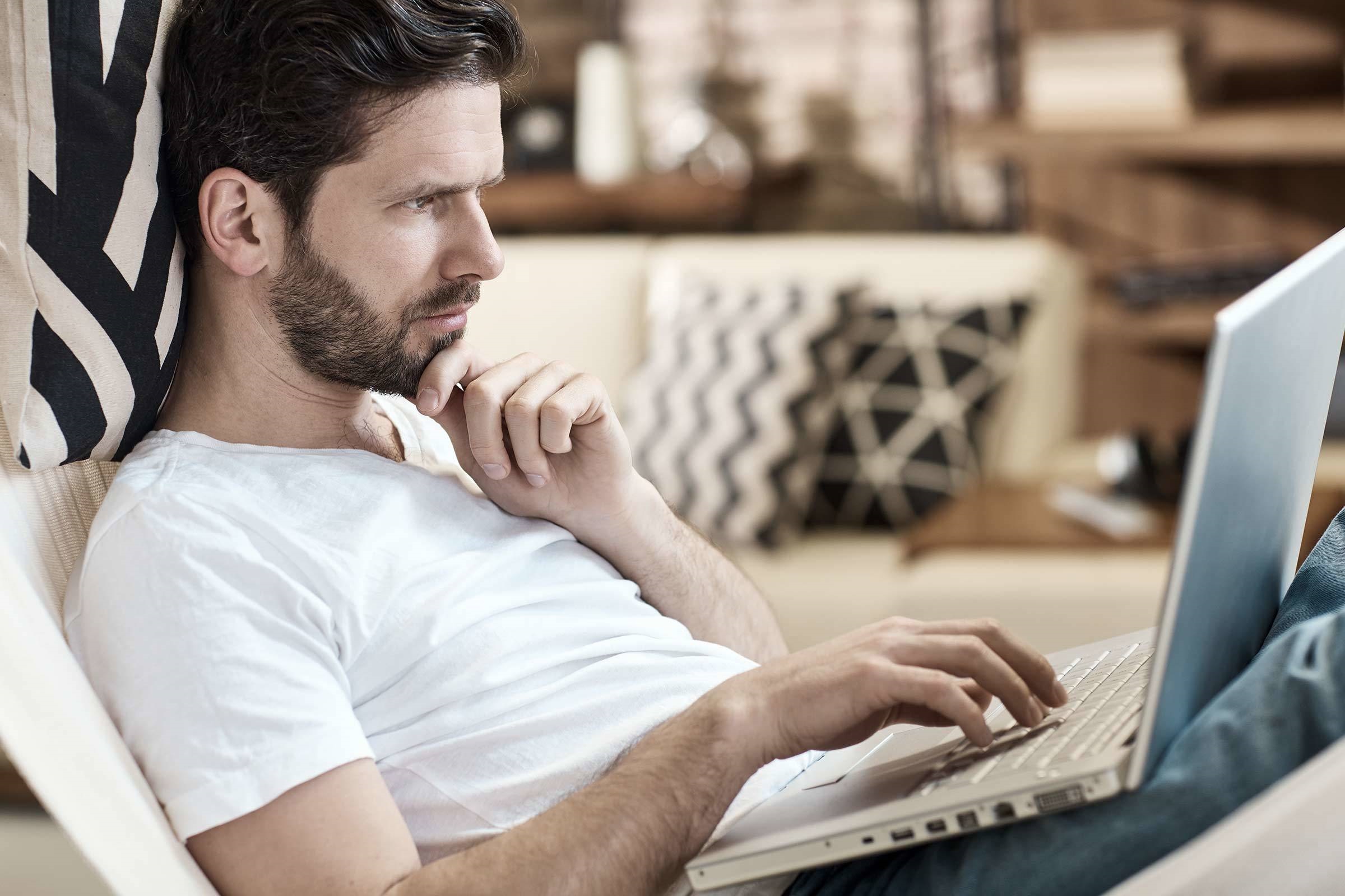 Baufinanzierung für Singles und Alleinverdiener: So klappt's Mann recherchiert am Laptop zu einer Baufinanzierung für Singles und Alleinverdiener