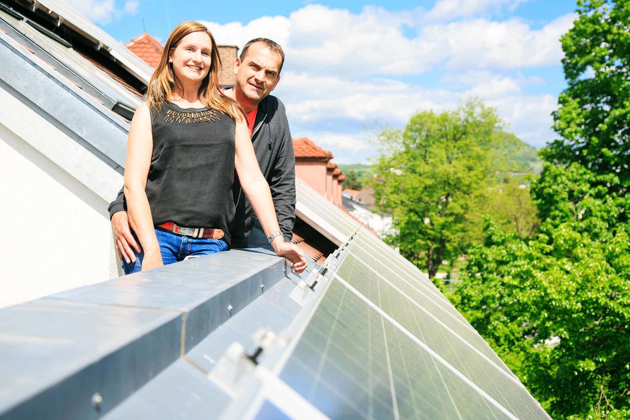 Energieeffizientes Haus bauen: Paar freut sich über Solaranlage auf dem Dach