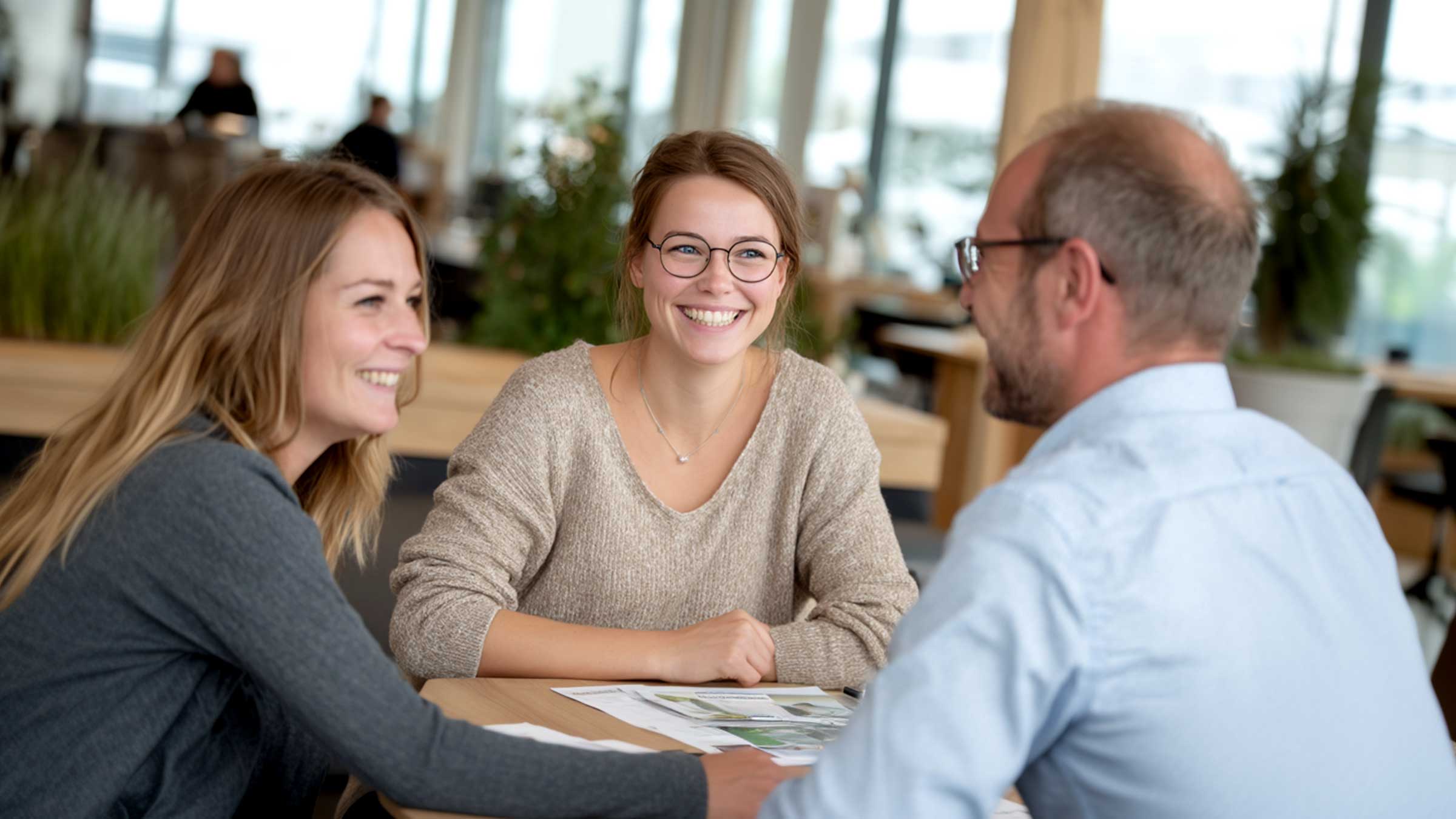 Ein Finanzvermittler berät zwei Frauen zur Baufinanzierung.