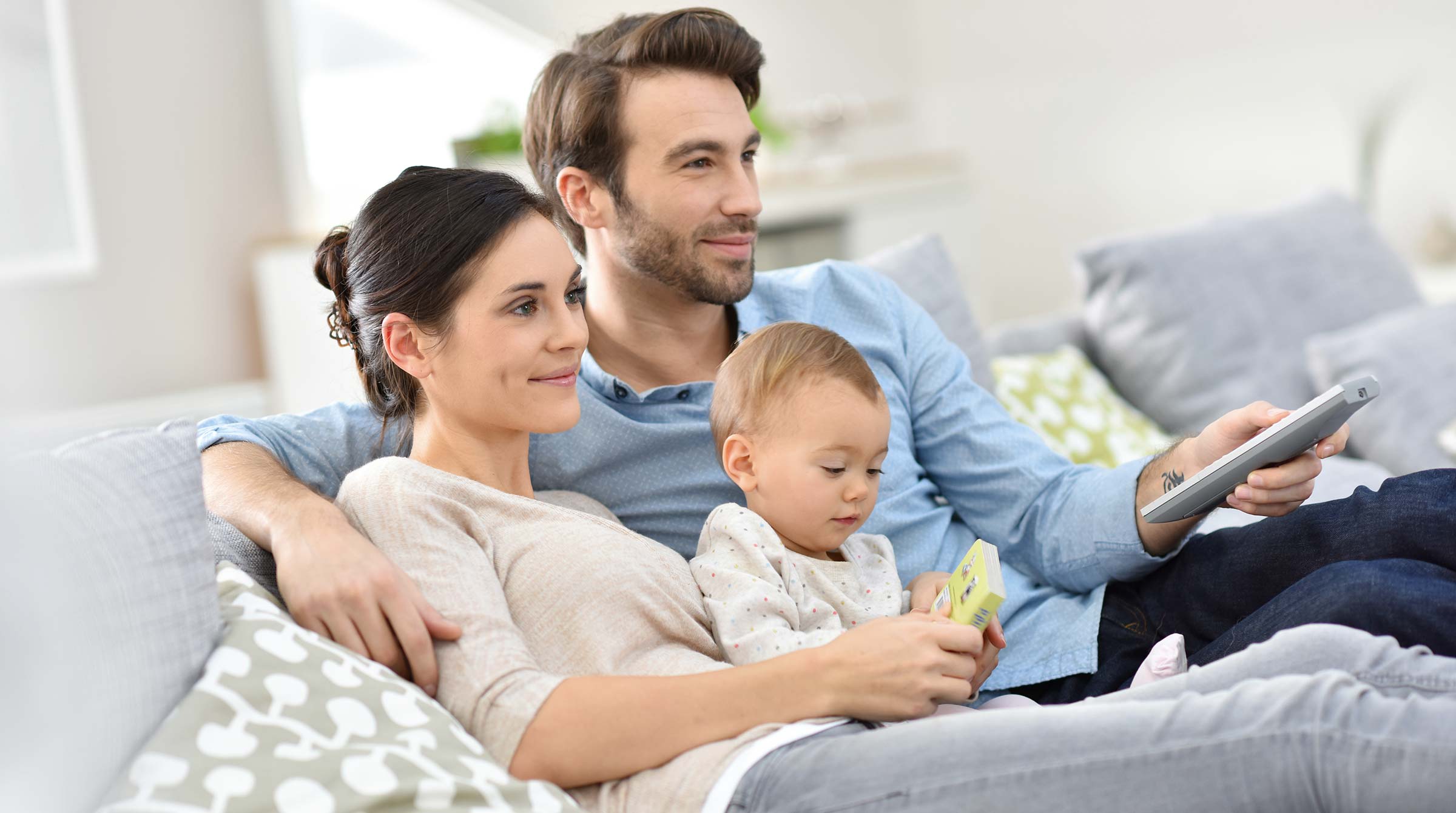 junges Ehepaar mit Baby auf dem Schoß sitzen auf dem Sofa