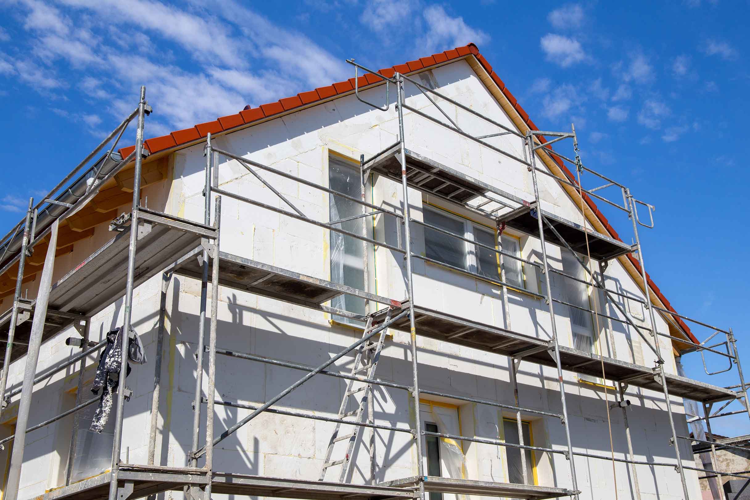 Eine Fassadensanierung mit einer Fassadendämmung wird mittels eines Baugerüst installiert 