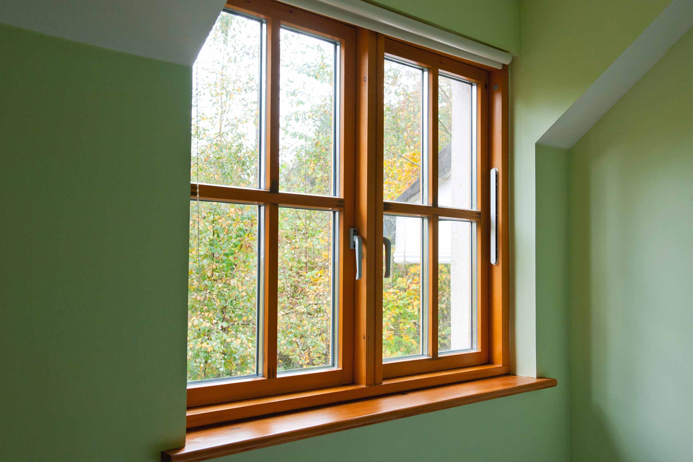 Ein schönes Holzfenster lässt viel Licht in einen grünen Raum einfallen